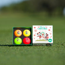 A set of four multicolored golf balls with Mickey and Minnie Mouse designs in a Christmas themed box, placed on a green grass surface.