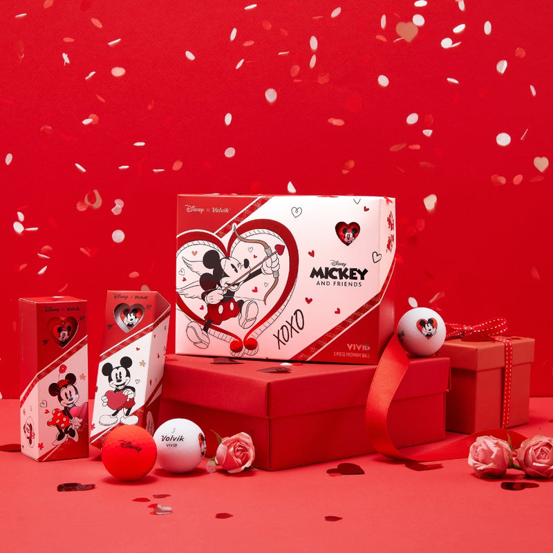 A set of golf balls with Disney characters Mickey and Minnie Mouse branding, presented with red and white themed packaging and decorations.